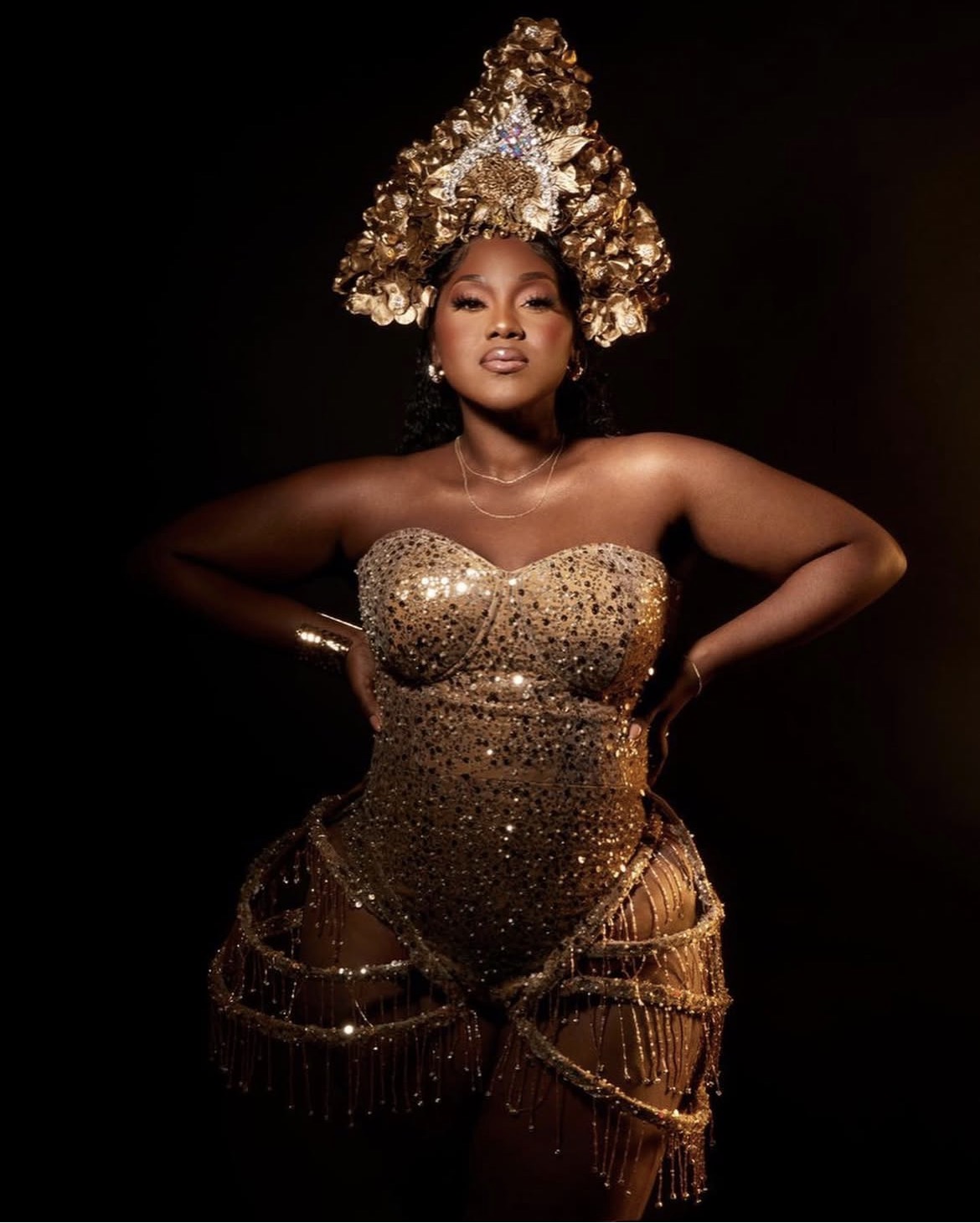 A client in a gold embellished gown with a sculpted gold headdress